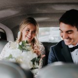 Nygift par i bröllopskläder sitter i bil