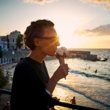 Kvinna med solglasögon äter glasstrut i solnedgång
