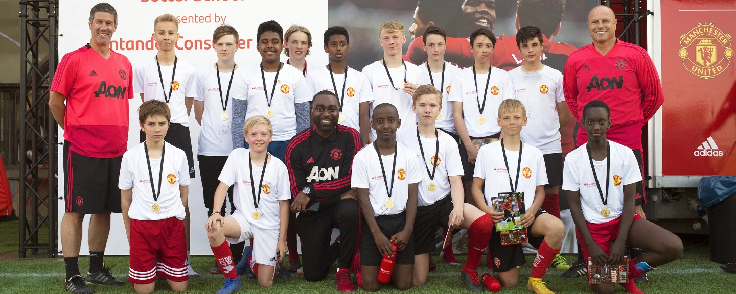 Ungdommar från Sandvikens IF med medaljer runt halsen och tränare från Manchester United