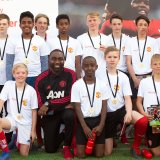 Ungdommar från Sandvikens IF med medaljer runt halsen och tränare från Manchester United