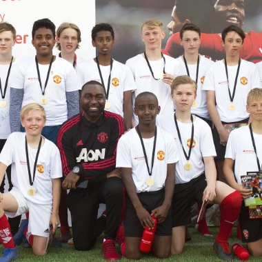 Ungdommar från Sandvikens IF med medaljer runt halsen och tränare från Manchester United