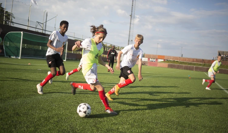 Fotbollstjej med gul väst dribblar