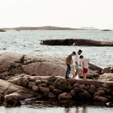 Pappa och söner på klipphällar vid havet håller fiskehåvar