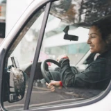 Kvinna i yrkeskläder kör minilastbil i stan