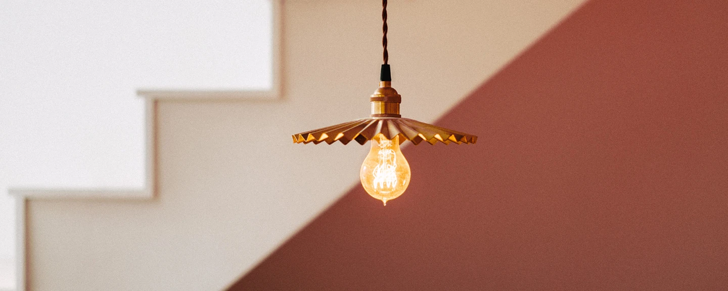 Låg vinkel av upplyst glödlampa som hänger mot trappa